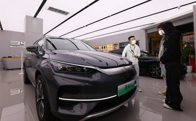 比亚迪店内，一名销售人员（左）正在向两位顾客介绍车辆信息。深圳特区报记者 杨浩翰 摄