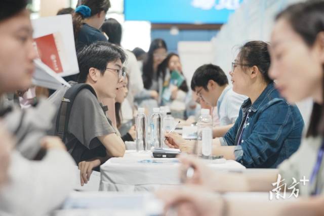 “百万英才汇南粤”武汉招聘会现场火爆，企业招聘展位座无虚席，面试洽谈对接需求。